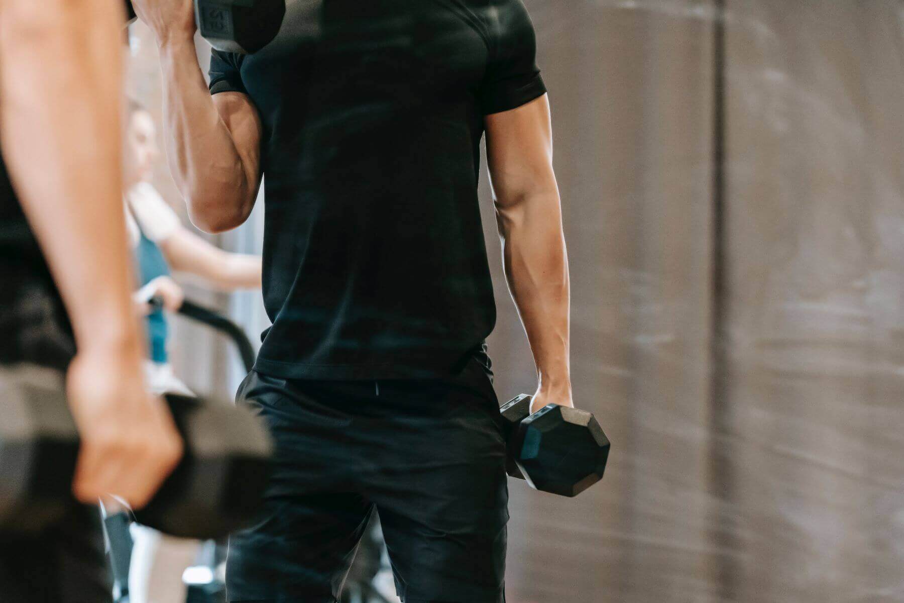 man in black shirt lifting dumbbells