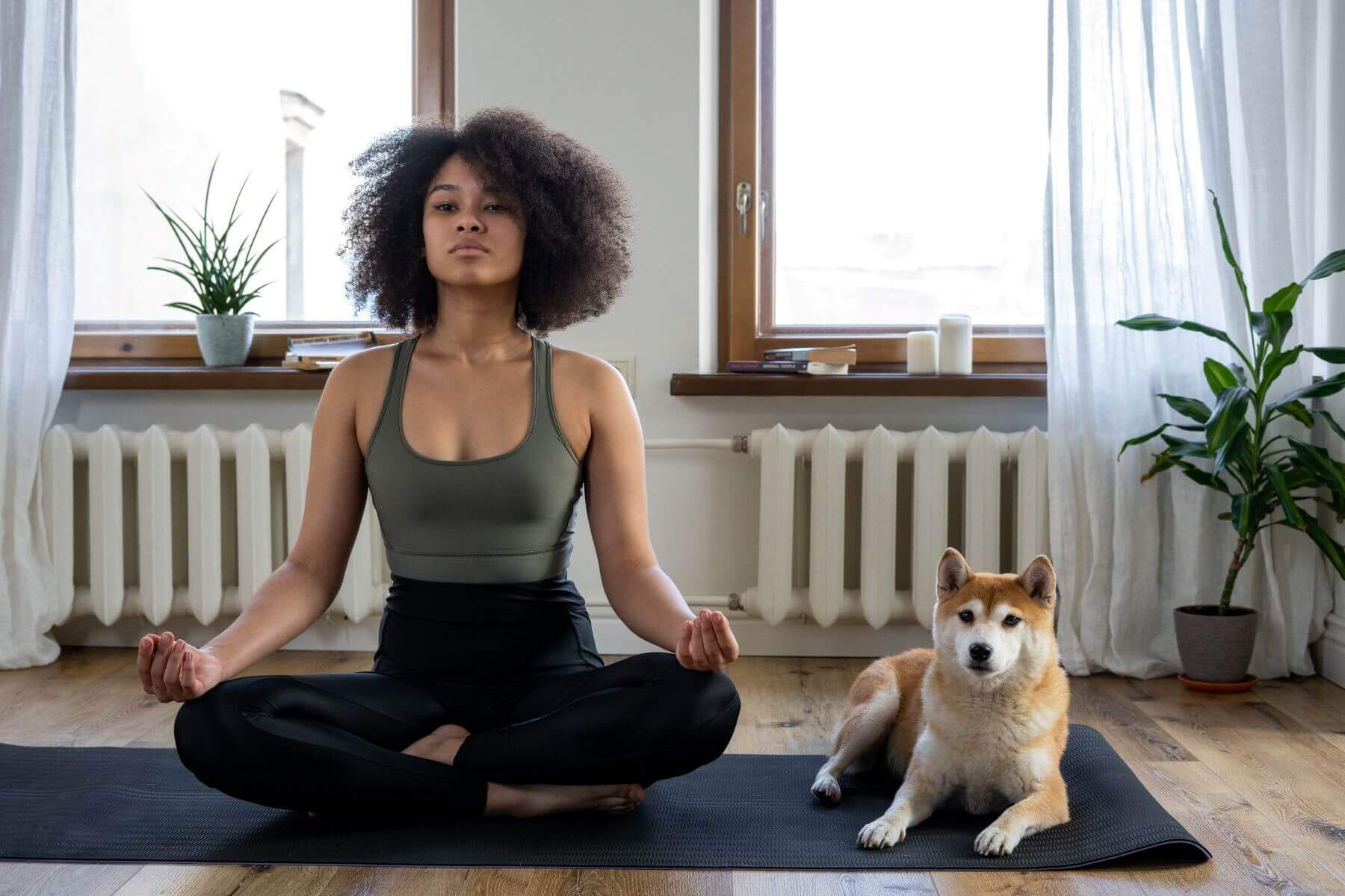woman doing yoga next to her dog