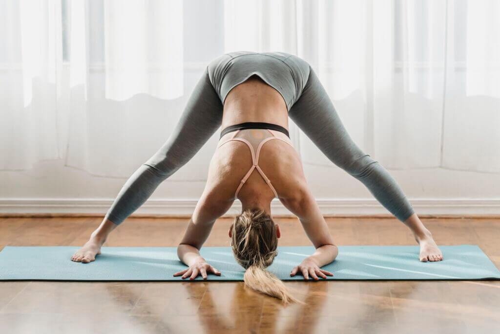 Mujer haciendo posture yoga con piernas anchas hacia adelante